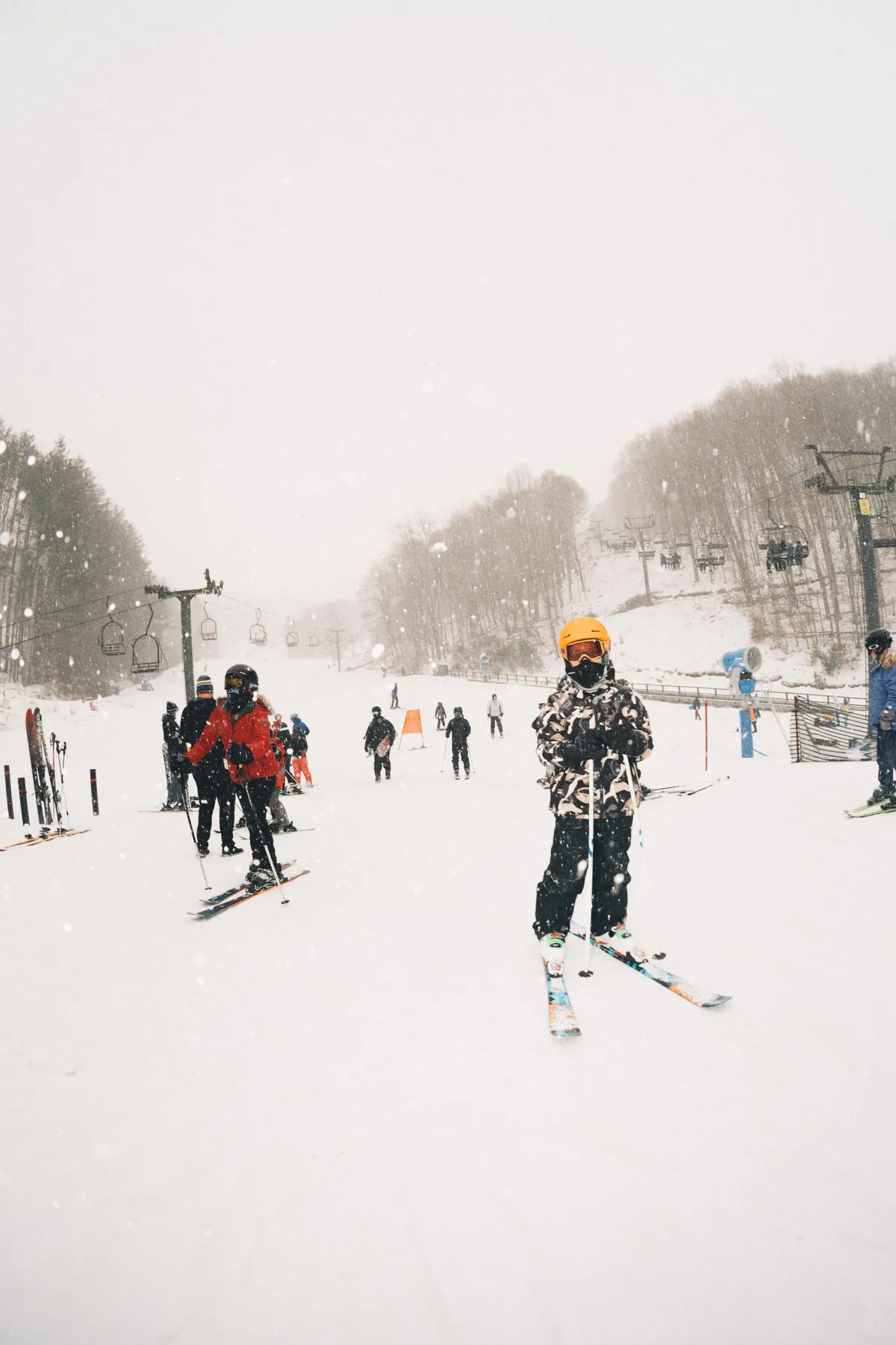 This image captures a lively winter scene with skiers, including children, enjoying the slopes under a ski lift. The entire landscape is blanketed in snow, emphasizing active participation in snow sports.